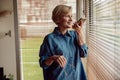 Middle aged woman recording audio message or using voicemail mobile function, standing near window Royalty Free Stock Photo