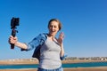 Middle-aged woman recording video on smartphone with outdoor on seashore Royalty Free Stock Photo