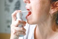 Middle-aged woman. With red hair. With a tired, sickly face. Sprays a spray for sore throat. On a gray background Royalty Free Stock Photo