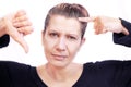 A middle-aged woman regrets that she has gray hair. She points her finger to the gray hair on her head. Isolated Royalty Free Stock Photo