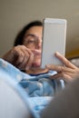 Middle-aged woman relaxing at home on the sofa reading her text messages on her mobile phone Royalty Free Stock Photo