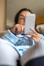 Middle-aged woman relaxing at home on the sofa reading her text messages on her mobile phone Royalty Free Stock Photo