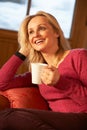 Middle Aged Woman Relaxing With Hot Drink On Sofa Royalty Free Stock Photo