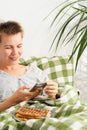 A middle-aged woman remains in bed, absorbed in her phone screen all day. Mental decline, sloth, inactivity