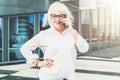 A middle-aged woman, a retired woman dressed in a white shirt and glasses, stands on a city street and talks on phone Royalty Free Stock Photo
