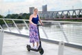 Middle-aged woman riding an electric scooter over a bridge