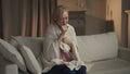 Middle-Aged Woman Experiencing a Coughing Fit While Seated on a Sofa Indoors