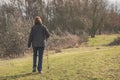 Middle-aged woman seen walking in a nature reserve using a walking pole.