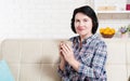 Middle-aged woman sits on couch and enjoys delicious hot drink after hard day`s work Royalty Free Stock Photo