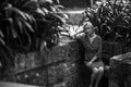 A middle-aged woman sits on a stone bench in old park. Black and white photo. Royalty Free Stock Photo