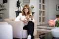 A middle-aged woman sitting in an armchair at home with her puppy on her lap Royalty Free Stock Photo