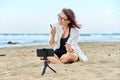 Middle aged woman sitting on beach with smartphone using video call Royalty Free Stock Photo