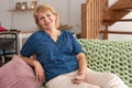Pretty middle aged woman sitting on sofa in room Royalty Free Stock Photo