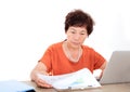 Middle-aged woman sitting in front of a laptop viewing financial documents Royalty Free Stock Photo