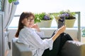 Middle-aged woman sitting at home in chair using digital tablet Royalty Free Stock Photo