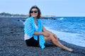 Middle-aged woman sitting on sea beach, traveling happy resting female looks at sea