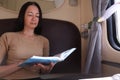 Middle aged woman sitting on sofa in compartment  of train and reading book Royalty Free Stock Photo