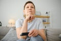 middle-aged woman sitting on the sofa and turning on the TV with a remote control. Royalty Free Stock Photo