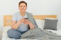 middle-aged woman sitting on the sofa and turning on the TV with a remote control. Royalty Free Stock Photo