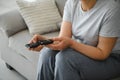 middle-aged woman sitting on the sofa and turning on the TV with a remote control. Royalty Free Stock Photo