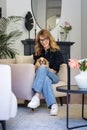 A middle-aged woman sittingnin an armchair at home with her puppy on her lap Royalty Free Stock Photo