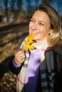 Middle aged woman with a smile holds an autumn yellow leaf near the face