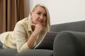 Middle aged woman solving sudoku puzzle on sofa Royalty Free Stock Photo