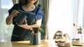 Middle aged woman standing at kitchen table, brewing drip coffee and enjoys her morning