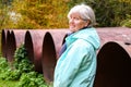 Middle aged woman standing outdoor in autumn near big old meal construction pipes Royalty Free Stock Photo