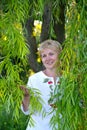 Middle-aged woman stands among willow branches Royalty Free Stock Photo