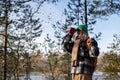 Focused woman tourist birdwatcher in autumn forest looking through binoculars on birds. Tourism.