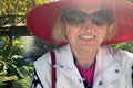 Middle-aged woman tourist wearing in red hat and sunglasses on waterfall with rainbow in jungles background Royalty Free Stock Photo