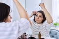 Middle aged woman treating her hair using medical drops.