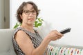 Middle-aged woman with a tv remote control Royalty Free Stock Photo