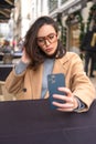 Middle-aged woman using smartphone sitting outdoor cafe