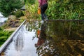 Middle aged woman walking across a flat roof of a carport flooded with rainwater to cleanup storm debris and clear drain blockage