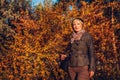 Middle-aged woman walking in autumn forest. Senior lady wearing stylish fall outfit with accessories