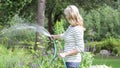 Middle Aged Woman Watering Garden With Hosepipe