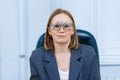 Middle-aged woman wearing glasses for eye exam in ophthalmologist's office.