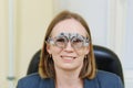 Middle-aged woman wearing glasses for eye exam in ophthalmologist's office.