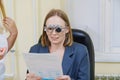 Middle-aged woman wearing glasses for eye exam in ophthalmologist's office.