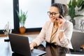 Middle-aged woman wearing wireless headset using a laptop computer Royalty Free Stock Photo