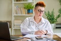 Middle aged woman working with computer papers, remote workplace in home office Royalty Free Stock Photo