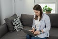 Middle-aged woman working from home. Girl using laptop at home, sitting on the sofa. Remote work concept