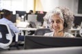 Middle aged woman working at computer with headset in office Royalty Free Stock Photo