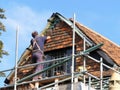 Middle aged workman standing on scaffolding fitting roof tiles to residential cottage Royalty Free Stock Photo