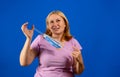 Middle blonde woman taking off her medical mask isolated on blue background