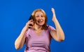 Middle blonde woman talking on smartphone over blue isolated background stressed with hand on head, shocked with shame