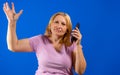 Middle blonde woman talking on smartphone over blue isolated background stressed with hand on head, shocked with shame