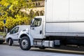 Middle class day cab rig semi truck with box trailer and cargo mini van make deliveries to customers standing on the city street